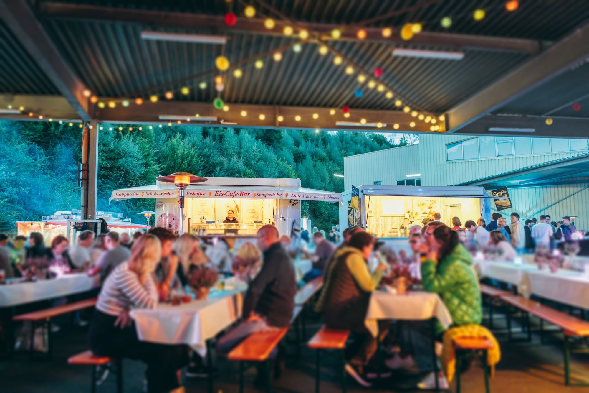 Summer party with mobile catering trailers and seating areas roughly 75% full