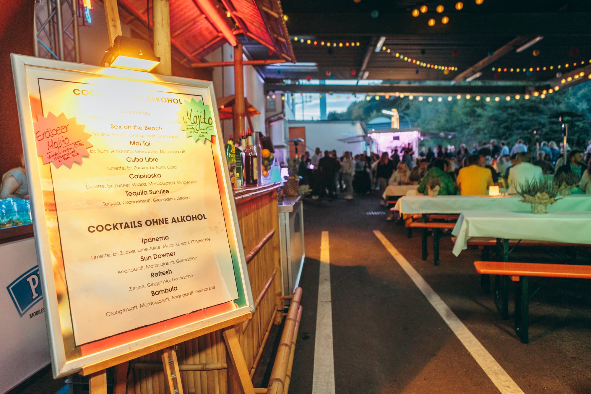 Cocktail menu at a summer party – bamboo bar and guests in the background
