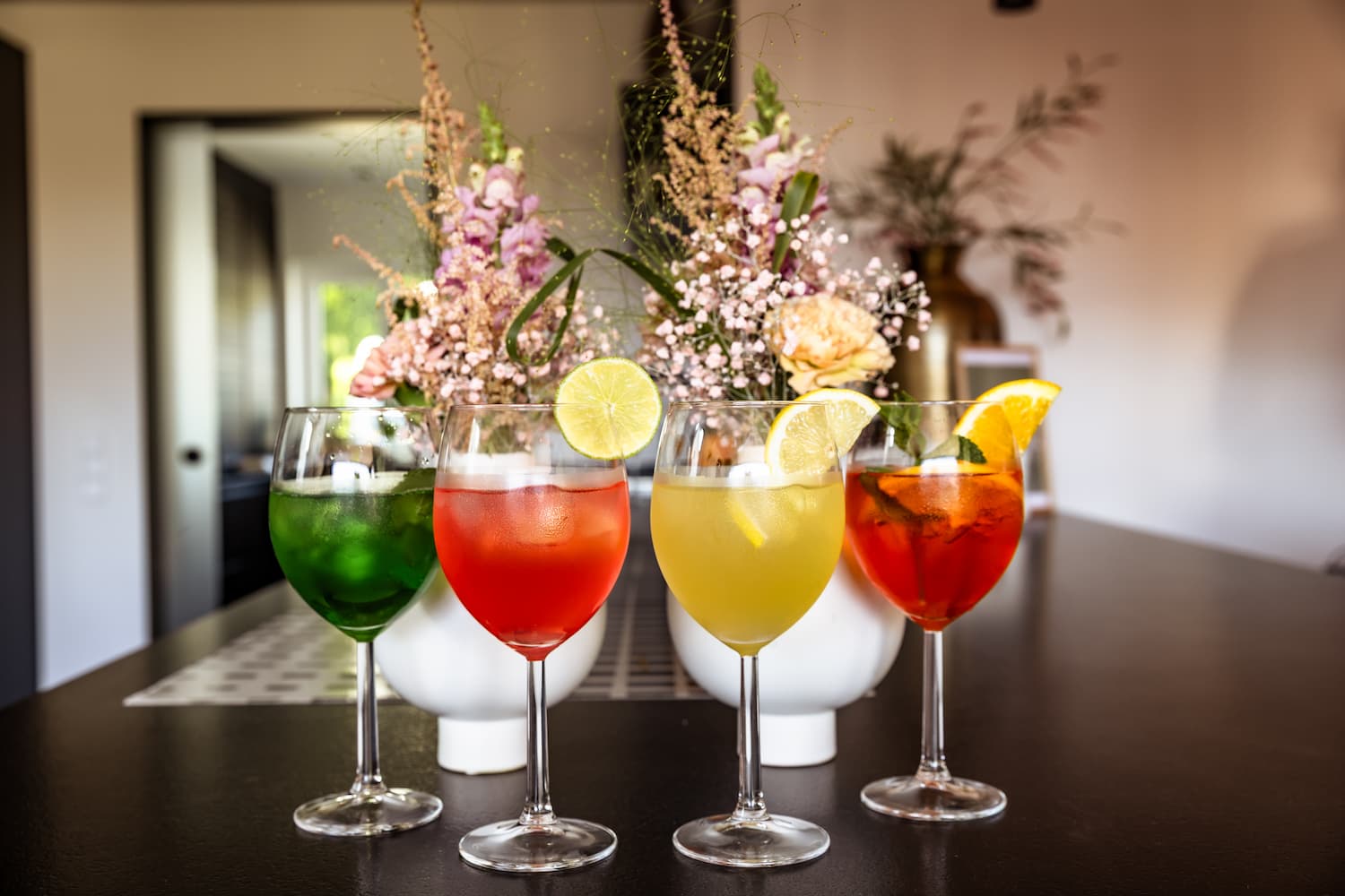 Four colourful cocktails in a row at a wedding, landscape format