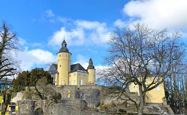 Schloss Homburg in Nümbrecht – historische Burganlage mit gelbem Schloss und steinernen Mauern unter blauem Himmel